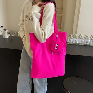 Hot pink embroidered monster tote bag with matching mini pouch on simple background