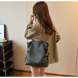 Detail view of grey polka dot tote bag with chain strap on a khaki blazer outfit
