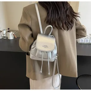 Close-up of silver mini backpack with drawstring and metallic texture on a model