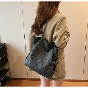 Detail of grey polka dot tote bag with metal chain strap worn with a blazer