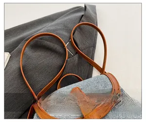 Detail of adjustable brown leather straps with fine stitching on a grey fabric backpack