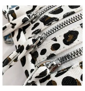 Détail du sac cabas léopard en toile avec trois fermetures éclair argentées et multiples compartiments