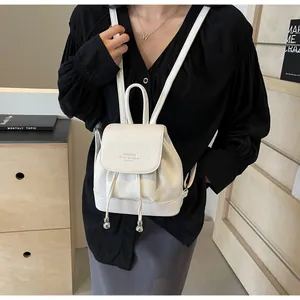 Close-up of white pebble leather mini backpack with drawstring and silver bead details