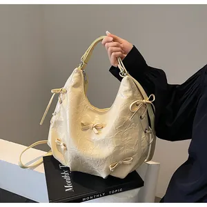 Detail of creamy white textured hobo bag with 3D bow decorations and adjustable strap