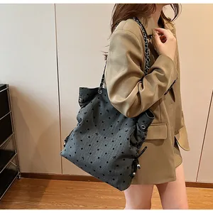 Chic grey tote bag with polka dot and bow patterns worn over a brown suit