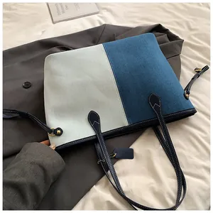 Détail du cabas en denim bicolore avec poignées en cuir et coutures en goutte