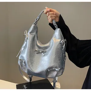 Detail of silver metallic tote bag with decorative bows and pleated texture for women