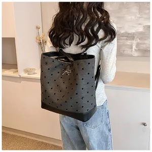 Dettaglio dello zaino tote grigio a pois con fiocco in metallo sulla modella