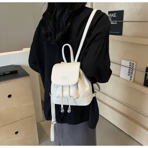Detail of a white mini leather backpack with drawstring closure on model back view