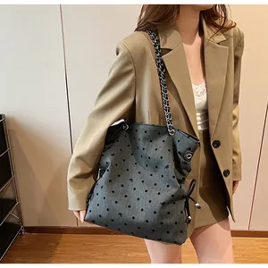 Detail of grey tote bag with polka dot pattern, metal chain strap and drawstring side