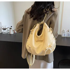 Detail of light yellow ruched tote bag featuring sweet bow accents and adjustable strap