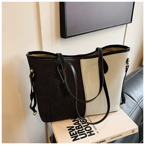 Détail du grand sac cabas en denim bicolore avec lanières noires et boucles latérales