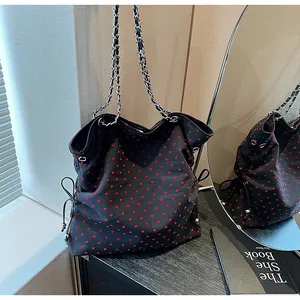 Detail of black tote bag with red heart patterns and silver chain leather strap