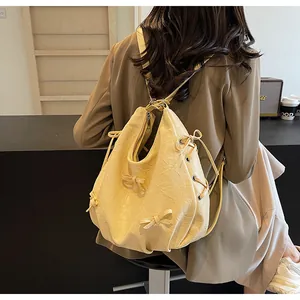Detail of cream yellow pleated tote bag featuring 3D bows and drawstring metal eyelets