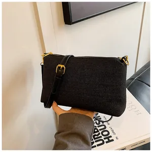 Détail du sac bandoulière en denim noir avec fermeture dorée et bandoulière en cuir