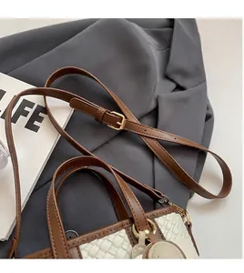 Detail of woven texture small tote with adjustable brown leather strap and gold buckle