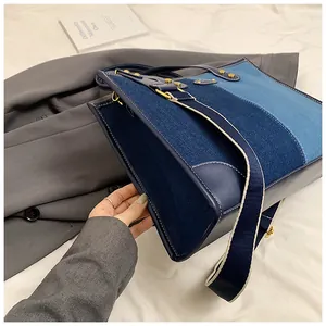 Detail of color-block denim tote bag with leather handles and woven shoulder strap