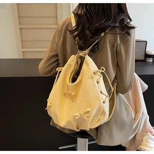 Detail of cream backpack with bow accents and drawstring on wrinkled faux leather