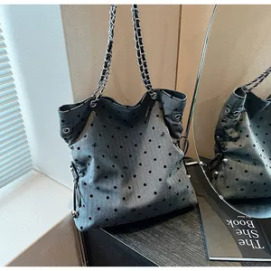 Detail of grey denim tote bag featuring black flocked polka dots and silver chain strap