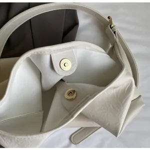 Détail du sac cabas blanc cassé montrant les boucles dorées et la texture du cuir
