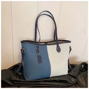 Détail du grand sac cabas en denim avec patchwork bleu et écru et poignées en cuir