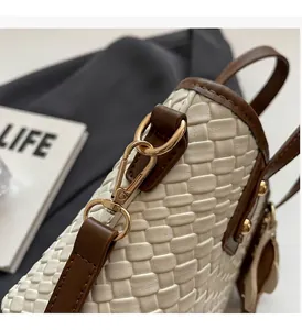 Close-up of golden hardware and woven texture on a cream tote bag with brown trim