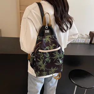Black waterproof crossbody bag with green leaf print and adjustable straps in street style