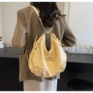 Detail of creamy yellow tote with ribbon bows and pleated leather texture on model