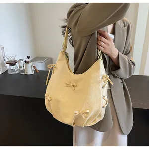 Detail shot of cream yellow hobo bag with pleated texture and decorative bow accent