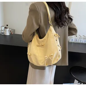 Close-up of cream yellow tote bag featuring 3D bows and textured vintage pleated fabric