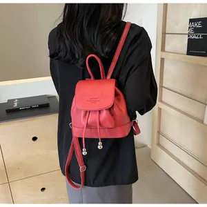 Close-up of a red textured leather mini backpack with silver drawstring metal balls