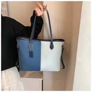 Détail du sac cabas en denim bicolore avec anses en cuir et boucle de réglage