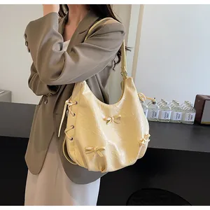 Detail of beige pleated leather tote bag with bow decoration and metal eyelet drawstring