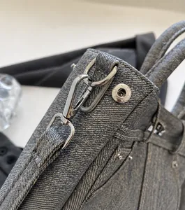 Detail van zilveren ster-knop en metalen haak op blauwe denim handtas voor dames