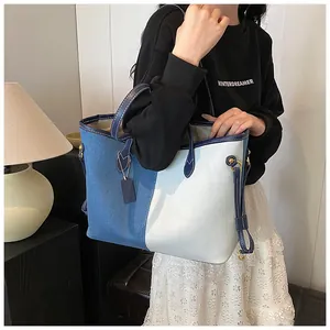 Détail du grand sac cabas en denim et toile bicolore avec sangles en cuir bleu