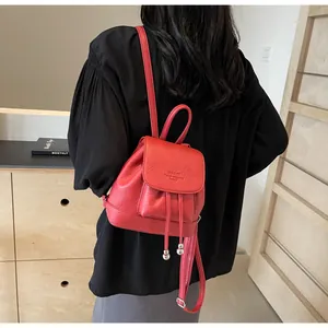 Detail of red mini backpack with pebbled leather texture and silver ball drawstring