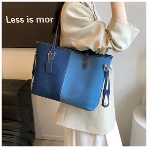 Détail d'un grand sac cabas en denim avec un design patchwork bleu et anses en cuir
