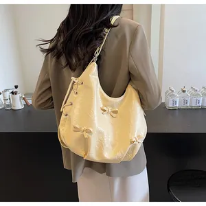 Detail of butter yellow wrinkled leather tote bag with 3D bows and drawstring side