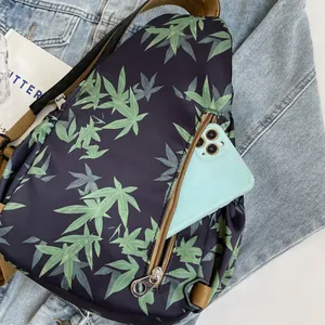 Detail of bamboo leaf print crossbody bag showing front zipper pocket with smartphone