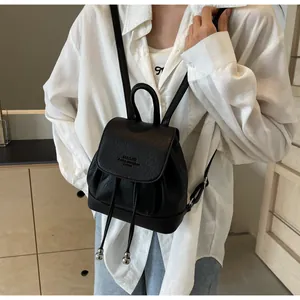Close-up of black pebble faux leather mini backpack with drawstring and flap closure