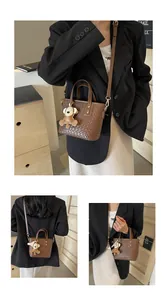 Detail of dark brown woven tote bag with adjustable strap and cute bear charm pendant