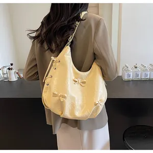 Detail of light yellow hobo bag with aesthetic bows and vintage wrinkled texture