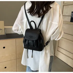 Close-up of mini black leather backpack with drawstring closure and pebble grain texture