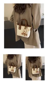 Detail of woven tote bag with a contrast teddy bear charm and adjustable shoulder strap