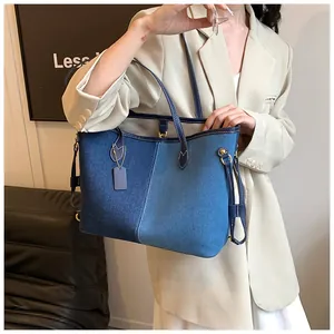 Détail d'un sac cabas en patchwork de denim avec boucles dorées et finitions en cuir