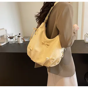 Pale yellow hobo bag with ribbon bows and drawstring details on a female model