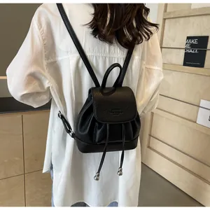 Detail of black pebbled leather mini backpack with drawstring and magnetic closure flap