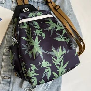 Detail of bamboo leaf print nylon mini crossbody bag with silver zippers and khaki strap