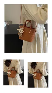Close-up of brown woven leather tote with decorative charm and metal rivet details