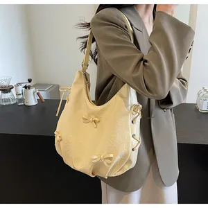 Detail of beige wrinkled leather tote bag featuring elegant side ribbon bow accents